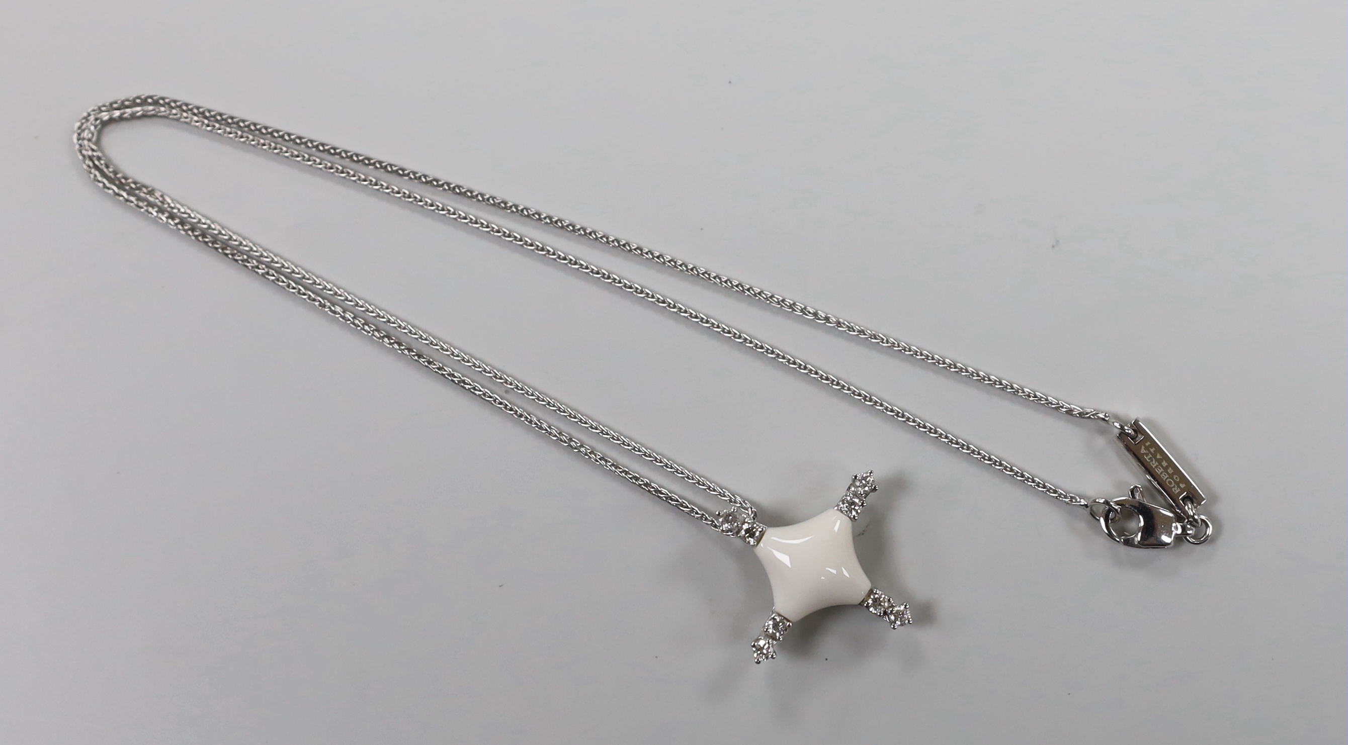 A modern Italian Roberta Porratti 18k white metal, six stone diamond and ceramic? set quatrefoil pendant, 23mm, on an 18k white meal chain, 40cm, signed, gross weight 7.5 grams.